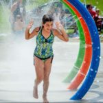 A girl runs through large coloured hoops that spray water in the new splash park.